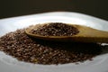 Flaxseeds spoon. Wooden spoon of flaxseeds on the white plate.