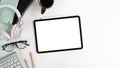 Top view white office desk with digital talet with empty screen , headphone, glasses, coffee cup and notebook. Royalty Free Stock Photo