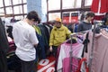 Flea market. Young man choosing second hand clothes at a shop, woman seller helping him Royalty Free Stock Photo