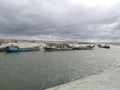 A fleet of fishing boats are moored together alongside a wharf and there are buildings above. Boat filled with sand Royalty Free Stock Photo