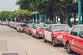 A fleet of Hong Kong taxis waiting at a taxi stand. Hong Kong taxis are easily recognizable by their red and white colors. The gen