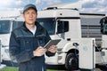 Fleet manager with a digital tablet stands next to electric trucks