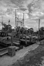 Fleet of shrimping boats docked along a river. black and white