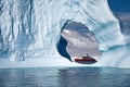 A small expedition vessel framed by a massive iceberg, Antarctica