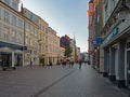 Passers-by stroll between stores in the busy Holm shopping street in Flensburg, Germany