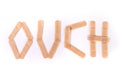 Flesh colored sticky bandage strips in forming the word ouch isolated over white