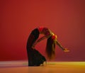 Flexibility and passion. Portrait of young girl dancing heels dance over red background in neon light. Concept of modern Royalty Free Stock Photo