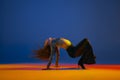 Flexibility and passion. Young girl dancing heels dance in stylish clothes over blue background in neon with mixed Royalty Free Stock Photo