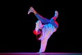 Flexible, artistic young man, breakdancer in motion, performing isolated over black studio background in neon light