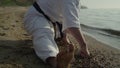 Flexible athletic man stretching on sand close up. Karate fighter exercising. Royalty Free Stock Photo