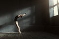 Flexible ballet dancer stretching in the dark lighted studio