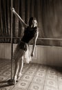 Flexible ballet dancer stretching in retro style. Ballerina dances near pole