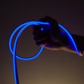 Flexible blue led tape neon in hand on black background Royalty Free Stock Photo