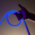 Flexible blue led tape neon in hand on black background Royalty Free Stock Photo