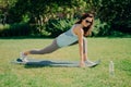 Flexible brunette girl in sportswear does exercises on fitness mat being in good physical shape wears sunglasses drinks water to Royalty Free Stock Photo