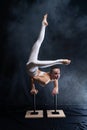 Flexible circus artist - female acrobat doing handstand on the back and smoker background. concept of willpower and