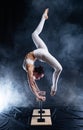 Flexible circus artist - female acrobat doing handstand on the back and smoker background. concept of willpower and