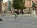 Flexible hipster girl balances in a standing pose, bending her leg back. Posing for a photo shoot in front of the