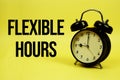 Flexible Hours text with alarm clock on yellow background Royalty Free Stock Photo
