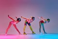 Flexible men in colorful, funny sportswear training, doing stretching exercises against gradient blue pink studio