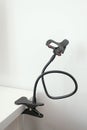 Flexible mobile phone holder on wall background. Multipurpose mobile accessory