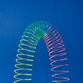 Flexible plastic rainbow spring on a blue background.