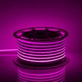 Flexible purple glowing LED neon strip on black background Royalty Free Stock Photo