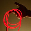 Flexible red led tape neon in hand on black background Royalty Free Stock Photo