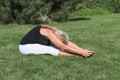 Flexible senior blonde woman is exercising outdoors