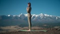 Flexible sportive young woman practices yoga on background of snow-capped mountains