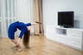 flexible woman exercising at home in front of tv screen, stretching her back. Concept of individuality, creativity and