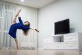 flexible woman exercising at home in front of tv screen, stretching her legs. Concept of individuality, creativity and
