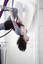 Flexible woman gymnast hangs upside down on the aerial hoop Royalty Free Stock Photo