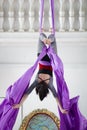 Flexible woman gymnast hangs upside down on the aerial hoop Royalty Free Stock Photo