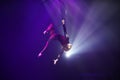 Flexible woman gymnast upside down on aerial hoop hold by one hand