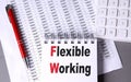 FLEXIBLE WORKING text on notebook with pen, calculator and chart on grey background