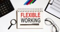 FLEXIBLE WORKING text in the office notebook with office tools, business concept