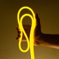 Flexible yellow led tape neon in hand on black background Royalty Free Stock Photo