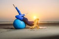 Flexible young girl with long blonde hair exercising on a yoga ball. Gymnast woman and big sports ball in the evening light