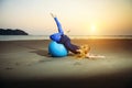 Flexible young girl with long blonde hair exercising on a yoga ball. Gymnast woman and big sports ball in the evening light