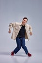 flexible young man in casual wear dancing in studio on gray background, alone. Royalty Free Stock Photo