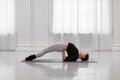 Flexible young woman doing setu bandhasana asana during yoga class in cozy bright room. The concept strengthens the neck