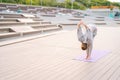 Flexible young yogini woman wearing sportswear standing on yoga mat and bending forward outdoors in summer morning. Royalty Free Stock Photo