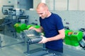 Flexo rotary die cutting preparation. Worker in printing factory, standing next to the printing machine preparing cylindrical die.