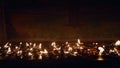 Flickering oil lamps illuminate Buddhist temple, creating serene, spiritual atmosphere. Devotional flames burn steadily