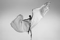 Black and white portrait of graceful ballerina dancing with fabric, cloth isolated on grey studio background. Grace, art