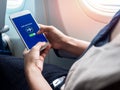 Flight mode concept. Hand holding white smartphone and turned on airplane mode on screen near the window on the airplane Royalty Free Stock Photo