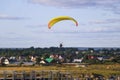 Flight of motor paraplan. a man flies on a bright colorful motoparaplane above the village, field and construction site.