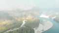 Flight over the banks of a mountain river. forest below, dawn of the sun, fog and clouds