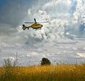 Flight over a field-taking off helicopter over a flowering meadow against a cloudy sky